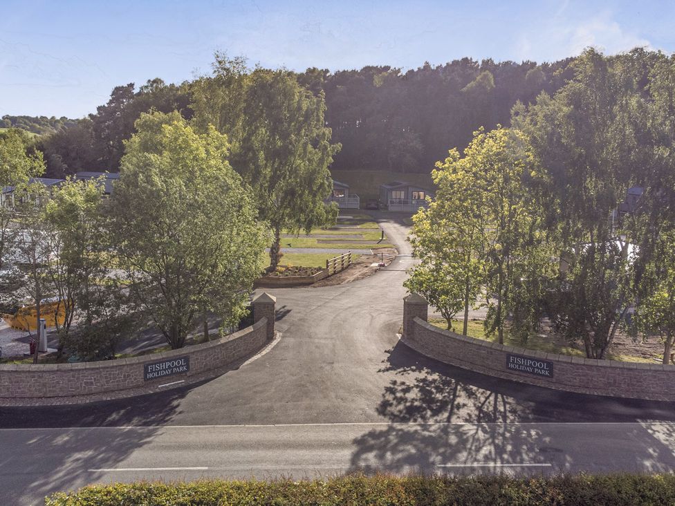 An outdoor view of Fishpool Holiday Park with trees and huts in Delamere