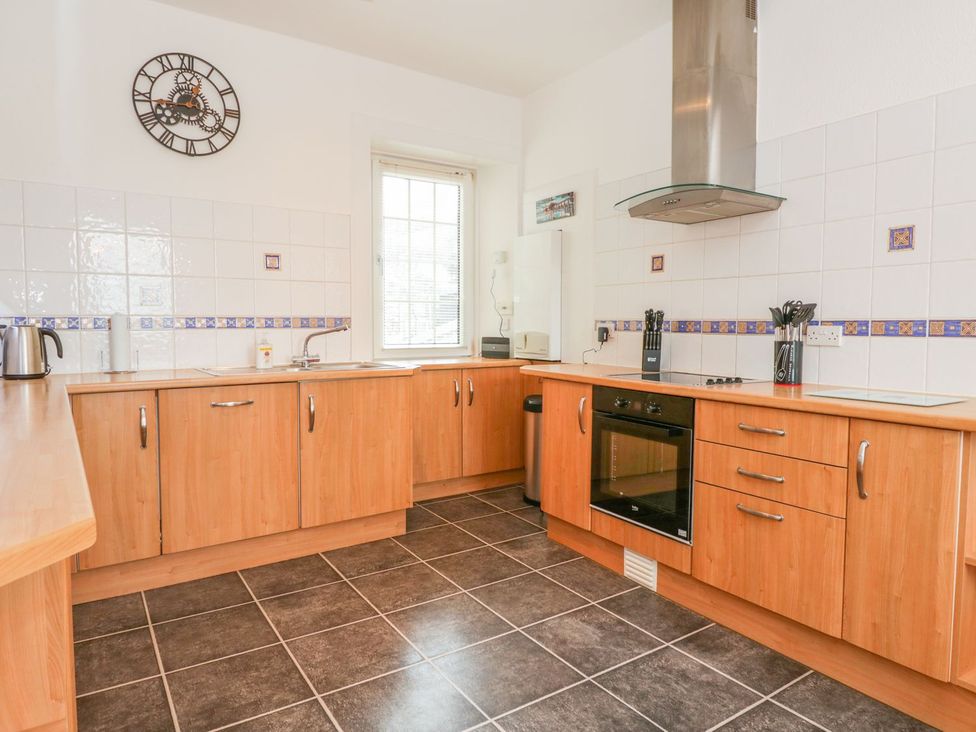 A kitchen with wooden cabinets and appliances at Maimie’s Harbourview Anstruther