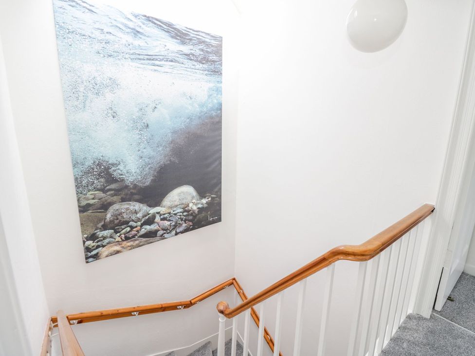 A staircase with wall art and light fixture at Maimie’s Harbourview Anstruther