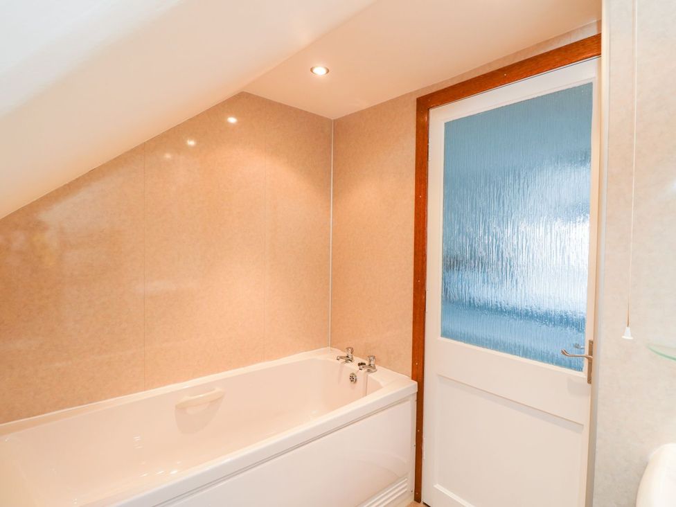 A bathroom with a bathtub and a door at Maimie’s Harbourview Anstruther