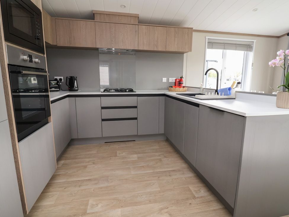 A kitchen with cabinets and appliances at Cedar Lodge 2 Bedrooms Delamere