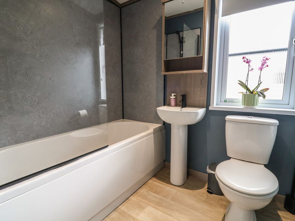 A bathroom with a bathtub, toilet, and sink at Cedar Lodge 2 Bedrooms in Delamere