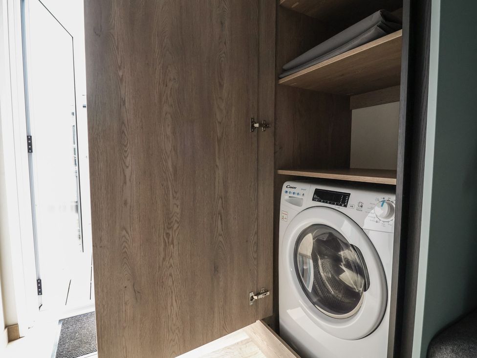 A laundry room with a washing machine and shelves at Cedar Lodge 2 Bedrooms, Delamere