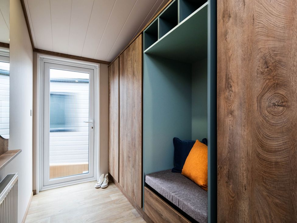 A hallway with a seating area and door at No 12 Whitefield Lodge Retreat, Northwich