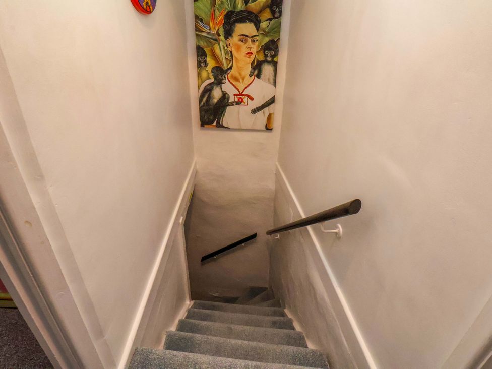 A staircase with a handrail and artwork on the wall at Frida's Cottage in Whitby