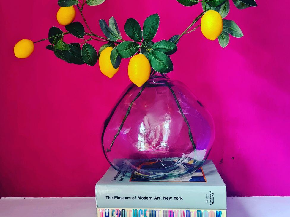 A vase with branches and lemons on top of books