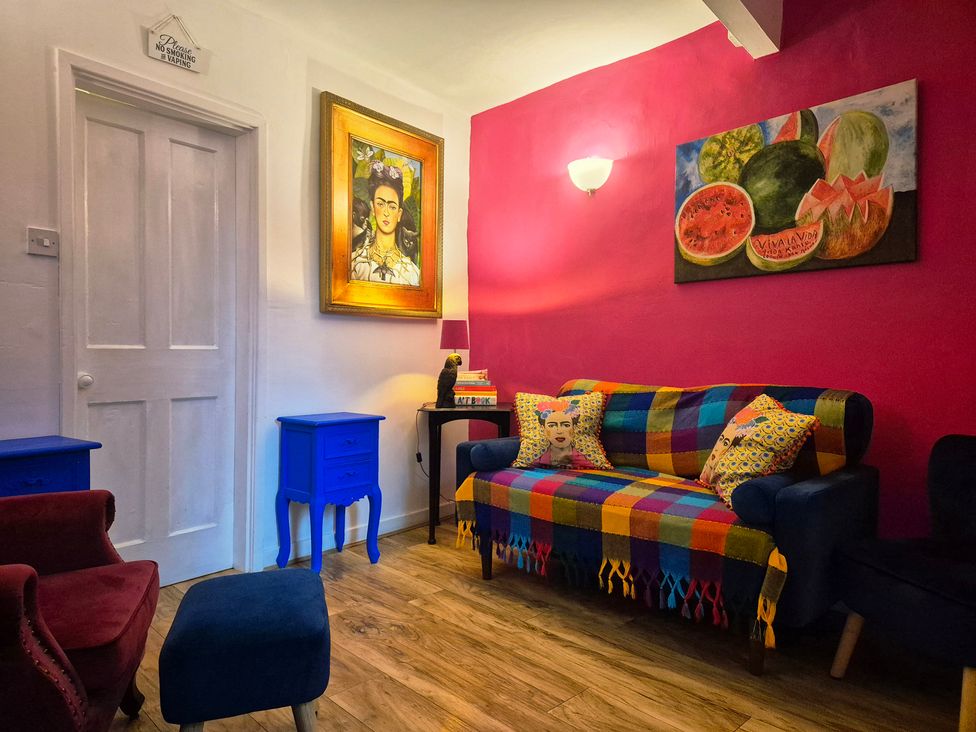 A living room with a colorful sofa art and side tables at Frida's Cottage in Whitby