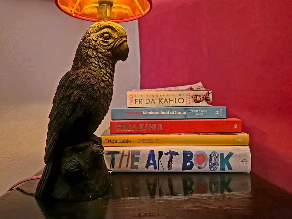 A lamp with a hawk sculpture and stacked books at Frida's Cottage in Whitby