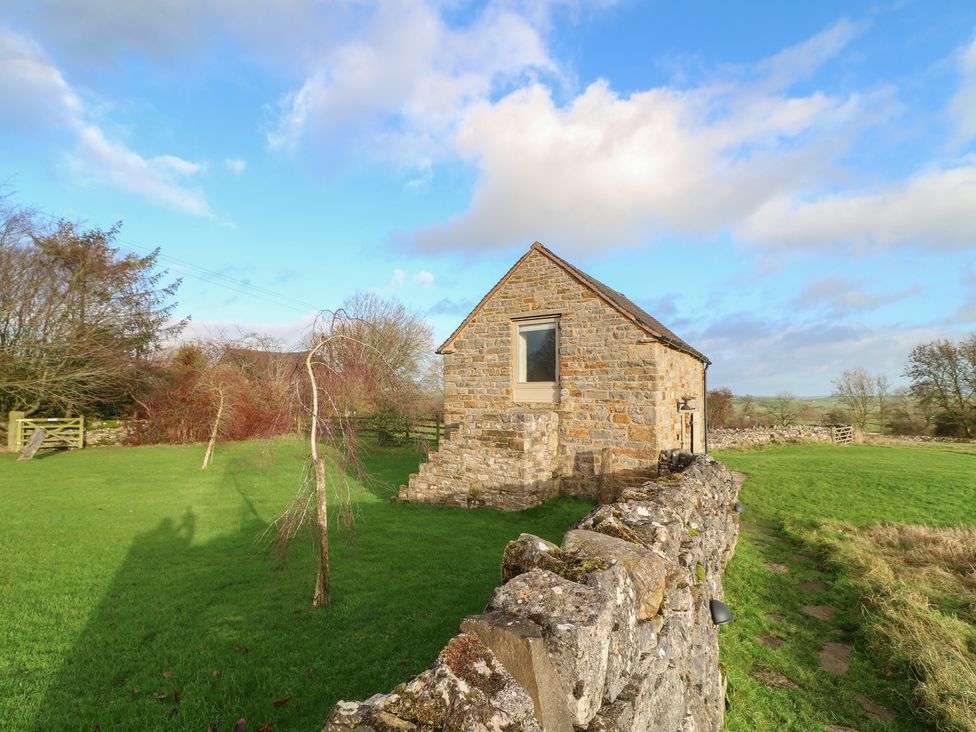 A stone building surrounded by grass and trees at Little Barn in Leek