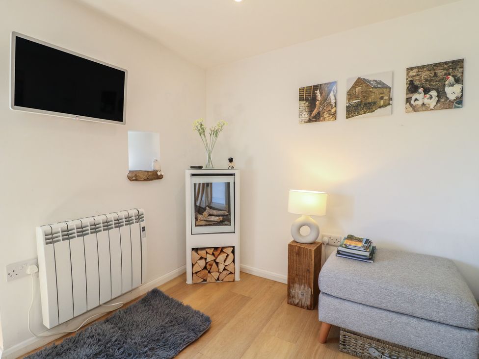 A living room with a television and an ottoman at Little Barn in Grindon