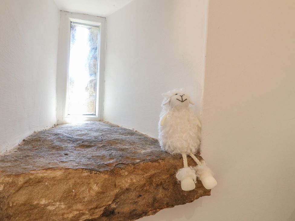 A stone ledge with a stuffed sheep toy next to a window at Little Barn in Grindon