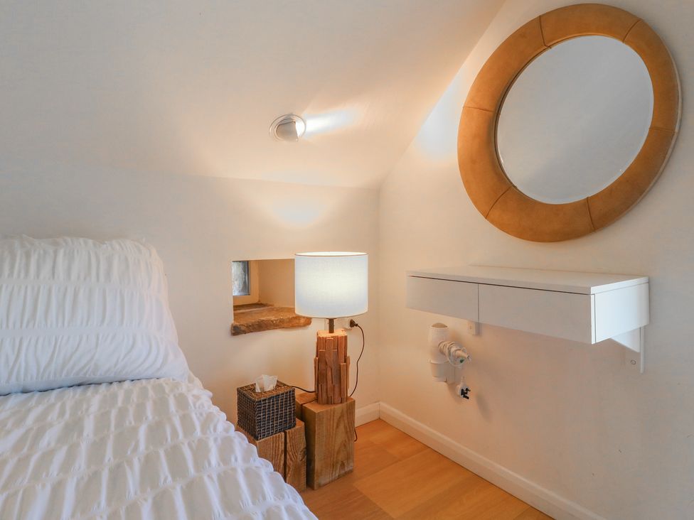 A bedroom with a bed, lamp, and mirror at Little Barn in Grindon