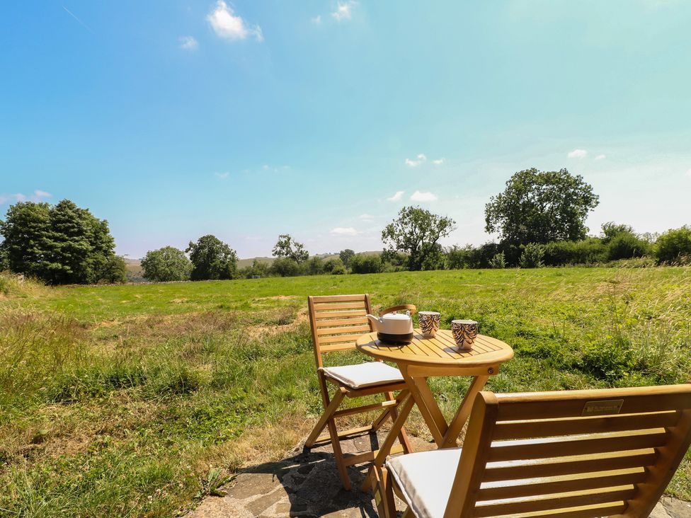 A table and chairs on grass with trees in the background at Little Barn in Grindon