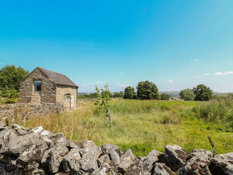 A stone building with a field and trees at Little Barn in Grindon
