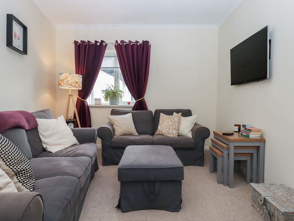 A living room with a sofa and television at Petitor Mews