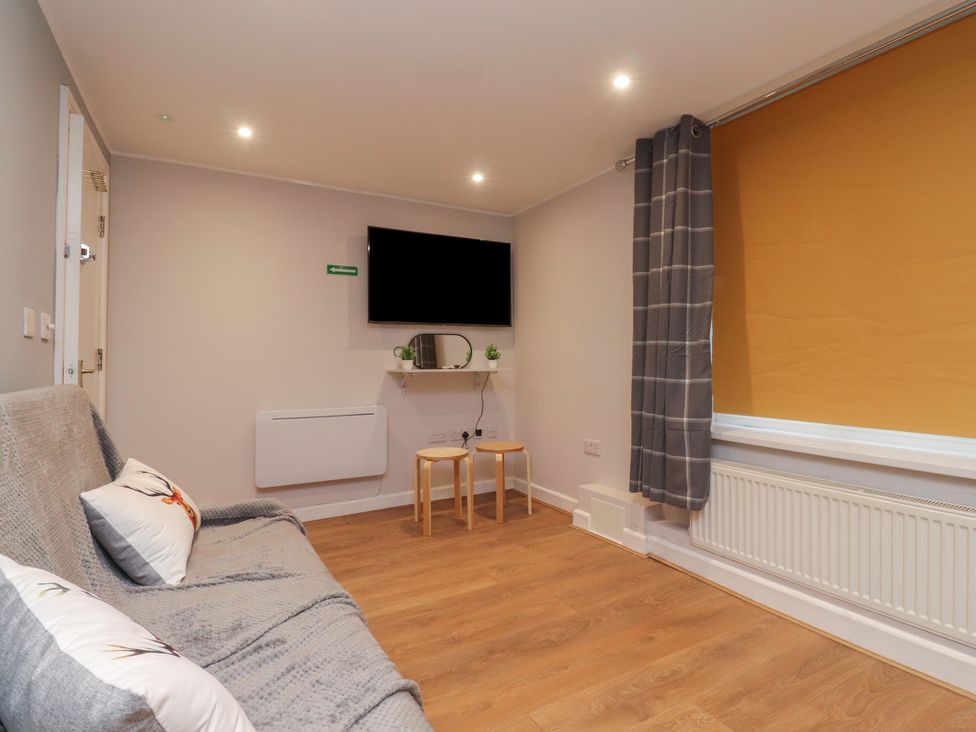 A living room with a sofa, television, and a small table at 38a Yorkshire Street