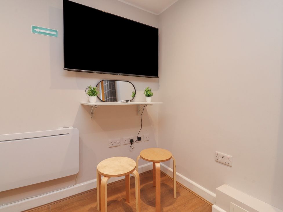 A room with a television, shelf, mirror, and two stools at 38a Yorkshire Street