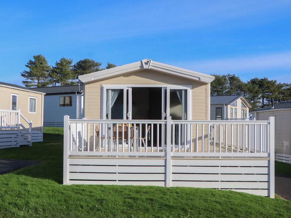 A static caravan with a deck and surrounding grass at Caravan C31 at Landscove Holiday Park in Brixham