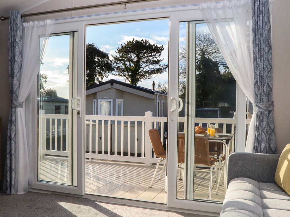 A living room with double doors leading to a balcony at Caravan C31 at Landscove Holiday Park Brixham