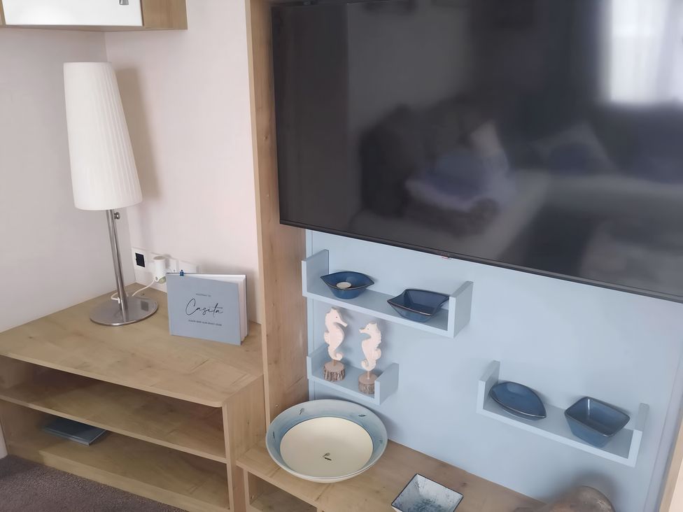 A living room with a lamp and television at 48 Woodland View Lymington