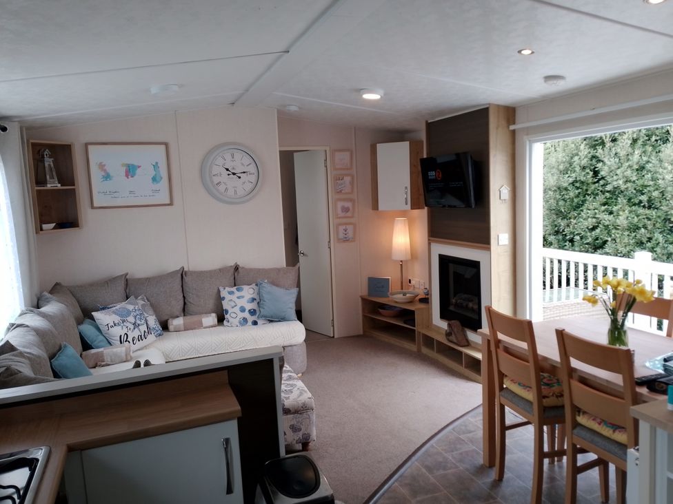 A living room with sofa and dining area at 48 Woodland View in Lymington
