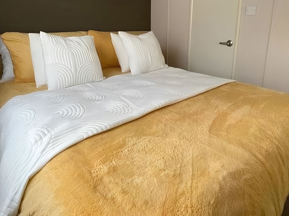 A bed with pillows and a yellow bedspread at 48 Woodland View in Lymington