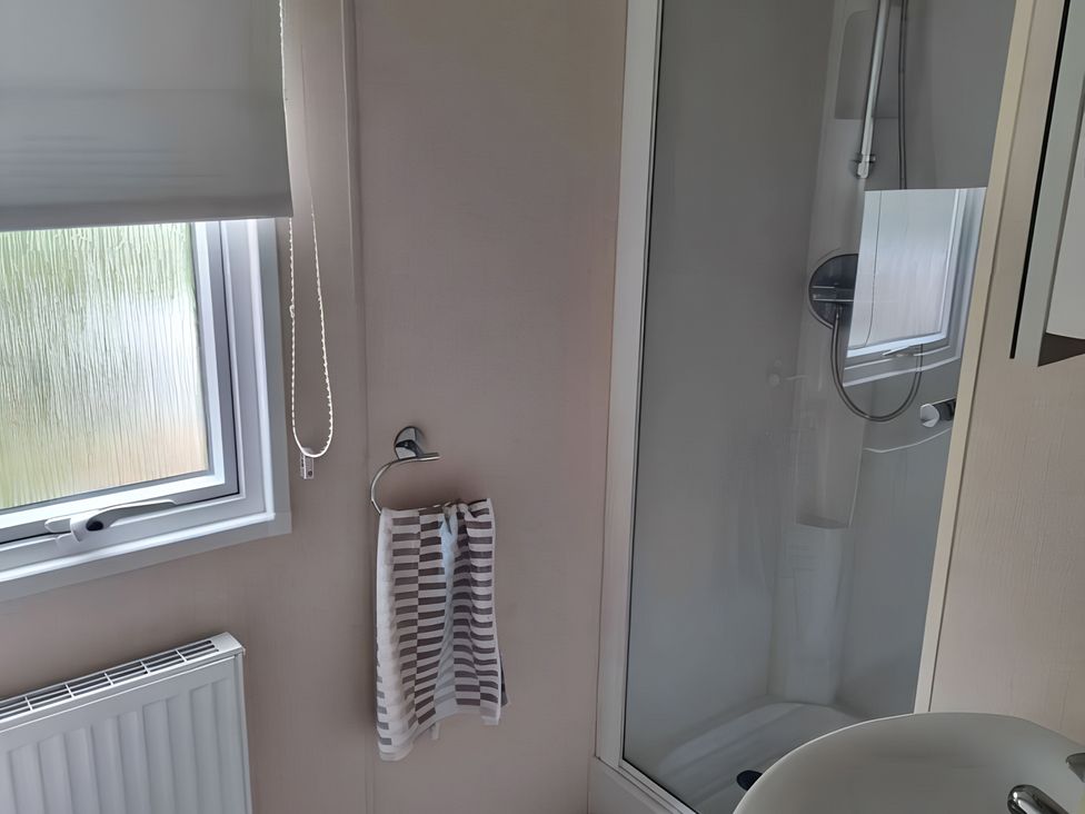 A bathroom with a shower and a window at 48 Woodland View in Lymington