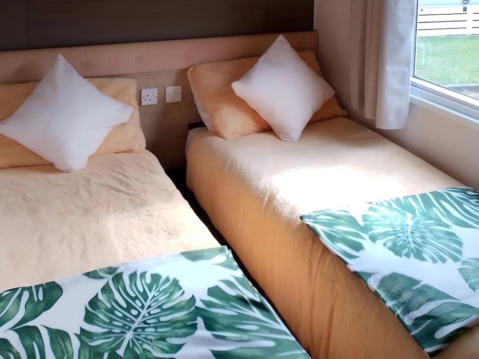 A bedroom with two single beds and a window at 48 Woodland View, Lymington