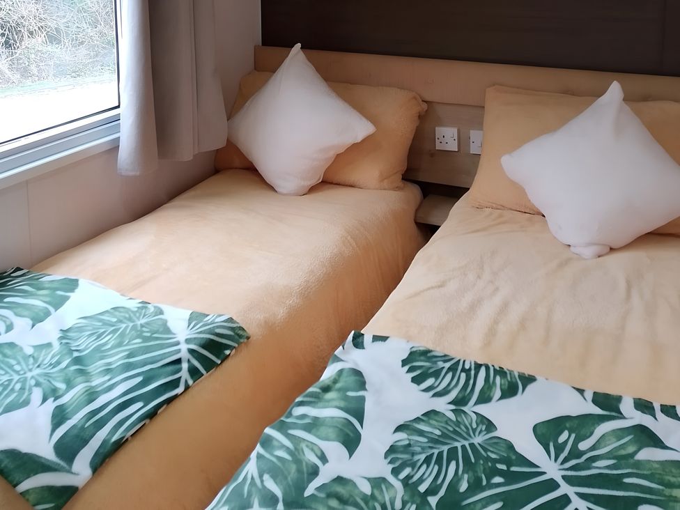 A bedroom with two beds and pillows at 48 Woodland View, Lymington