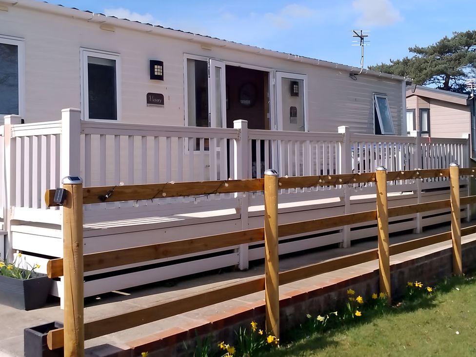 A cabin with a deck and railing at 48 Woodland View in Lymington