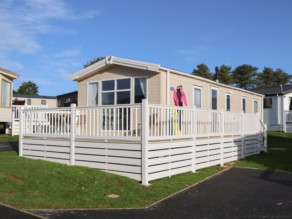 A caravan with a deck and a pink wetsuit hanging at Caravan C32 at Landscove Holiday Park in Brixham