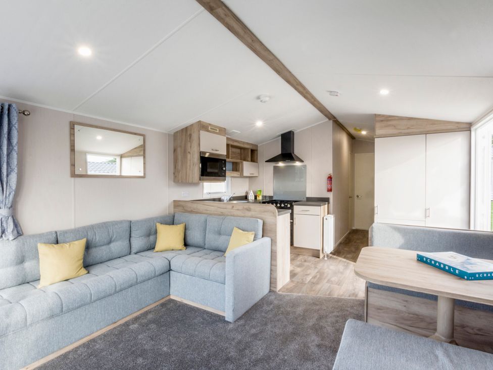 A living room with a couch and kitchen area at Caravan C32 at Landscove Holiday Park Brixham