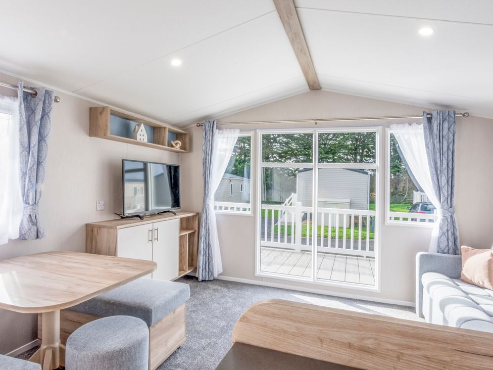 A living room with a television and a table at Caravan C32 at Landscove Holiday Park Brixham