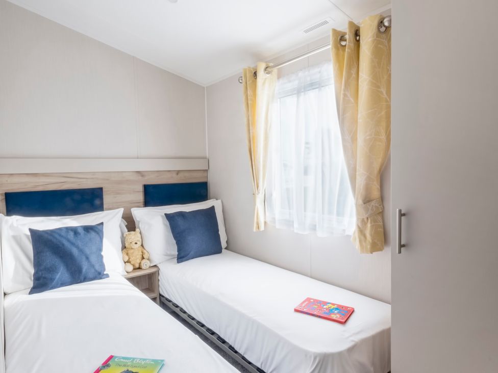 A bedroom with two beds and a window at Caravan C32 at Landscove Holiday Park Brixham