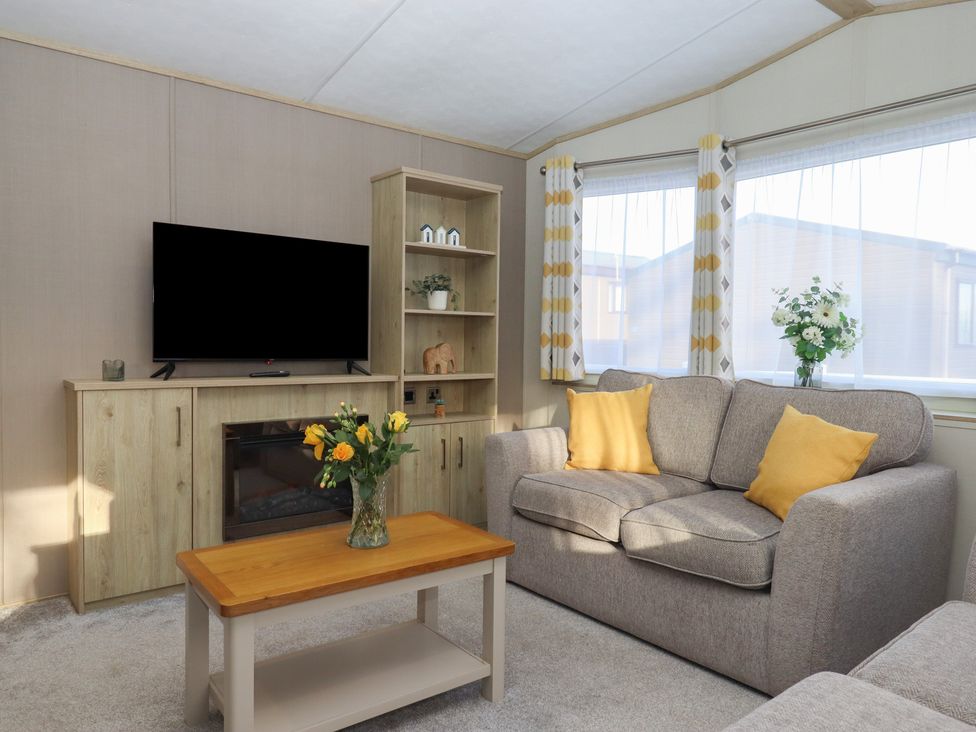 A living room with a sofa and television at Caravan A24 at Landscove Holiday Park Brixham