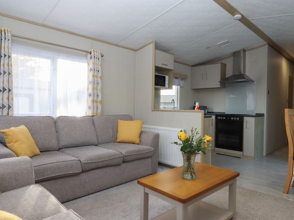 A living room with a sofa and kitchen area at Caravan A24 at Landscove Holiday Park Brixham