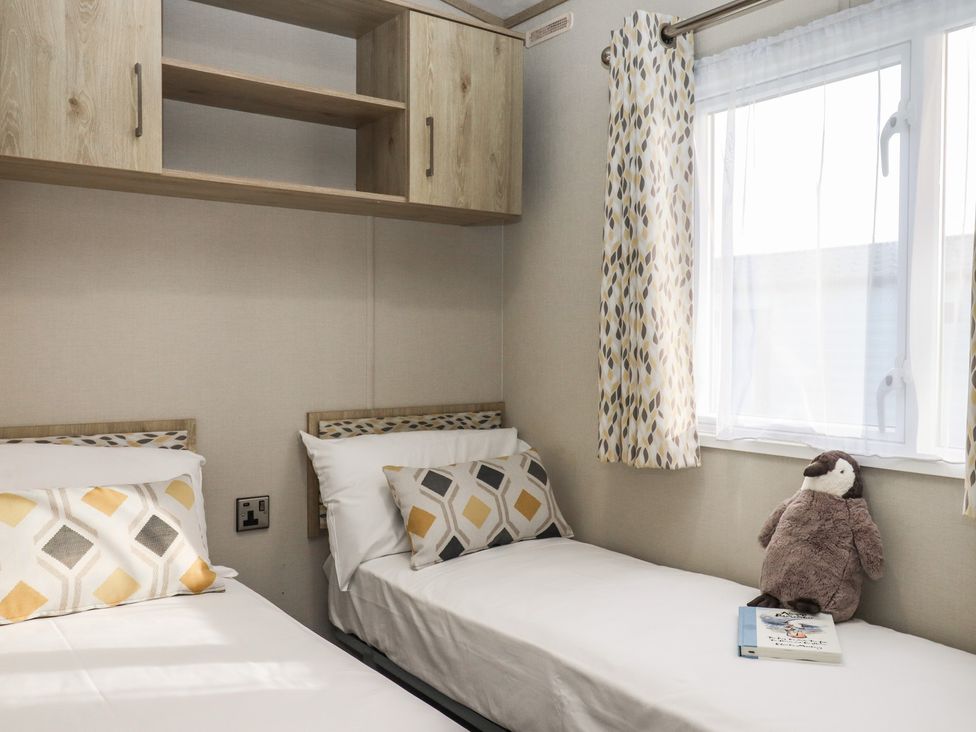 A bedroom with two beds and a shelf at Caravan A24 at Landscove Holiday Park Brixham
