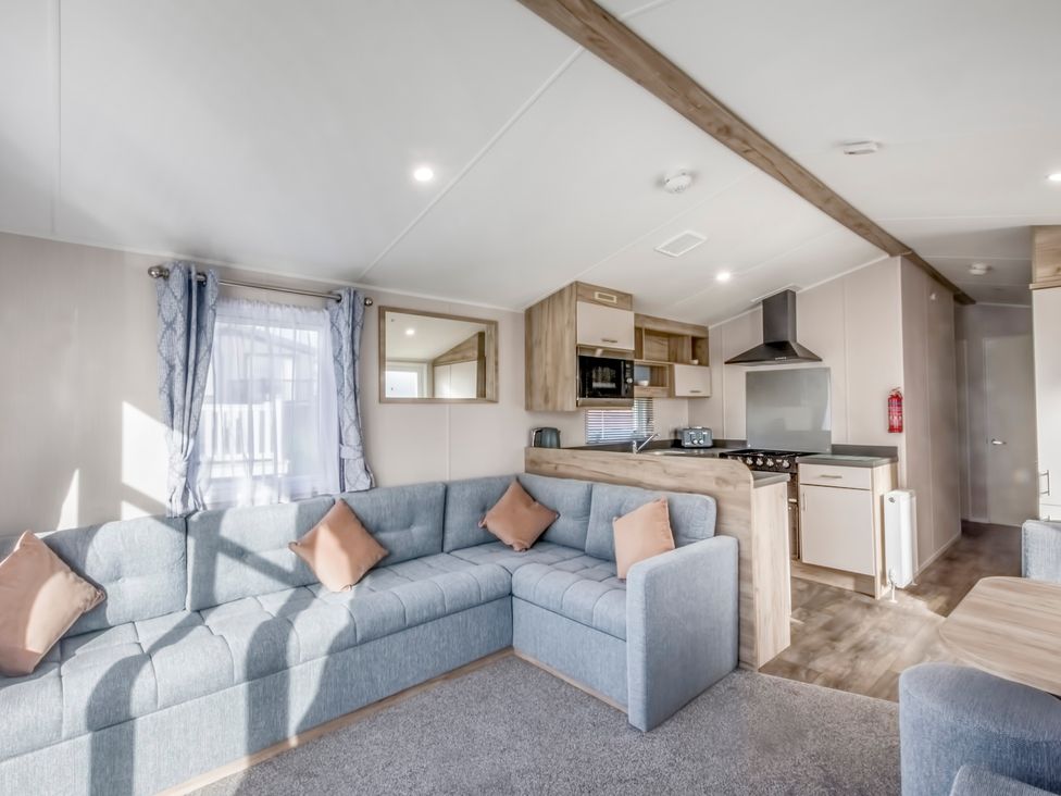 A lounge with a sofa and kitchen area at Caravan A24 at Landscove Holiday Park Brixham