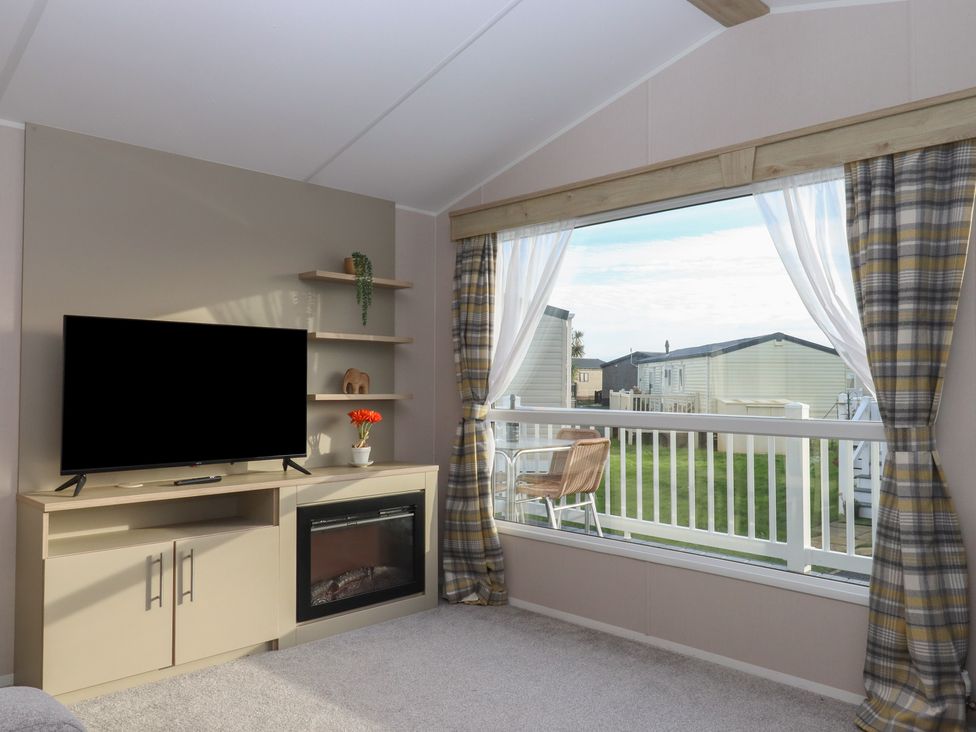 A living room with a television and electric fireplace at Caravan B61 at Landscove Holiday Park in Brixham