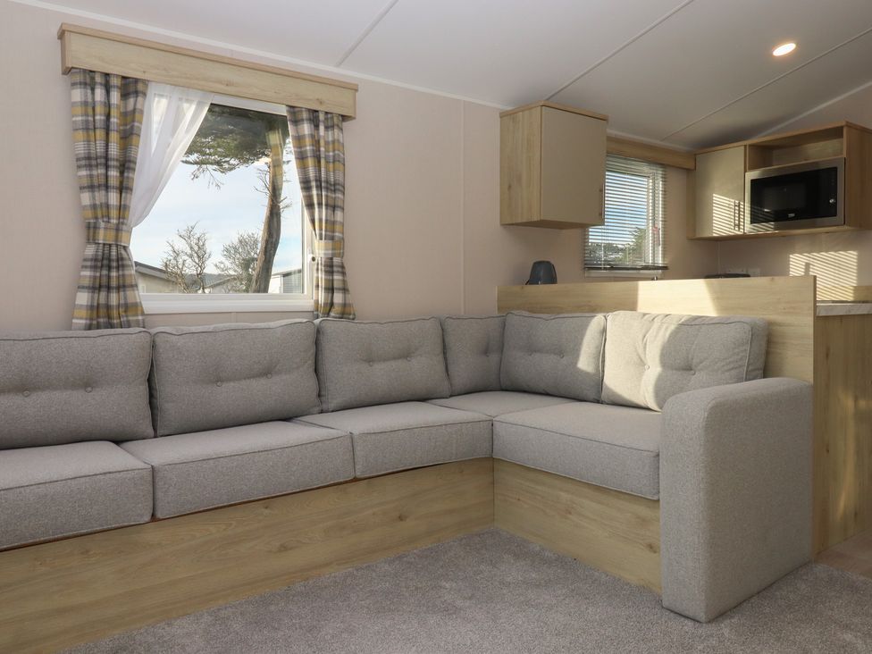 A living room with a sofa and microwave at Caravan B61 at Landscove Holiday Park in Brixham