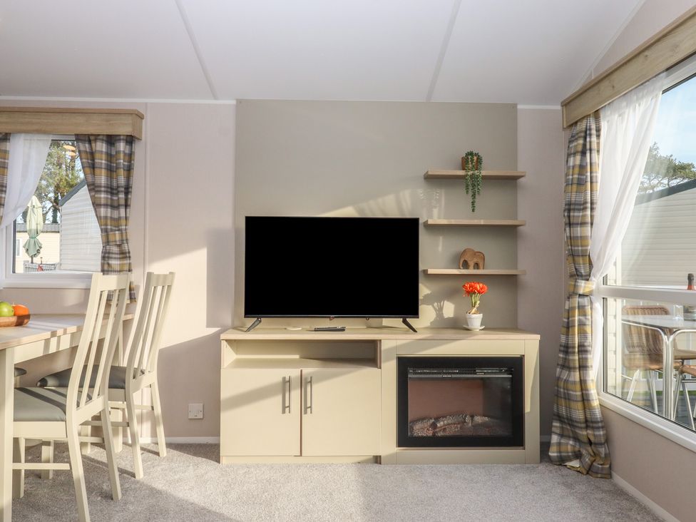 A living room with a television and dining table at Caravan B61 at Landscove Holiday Park in Brixham