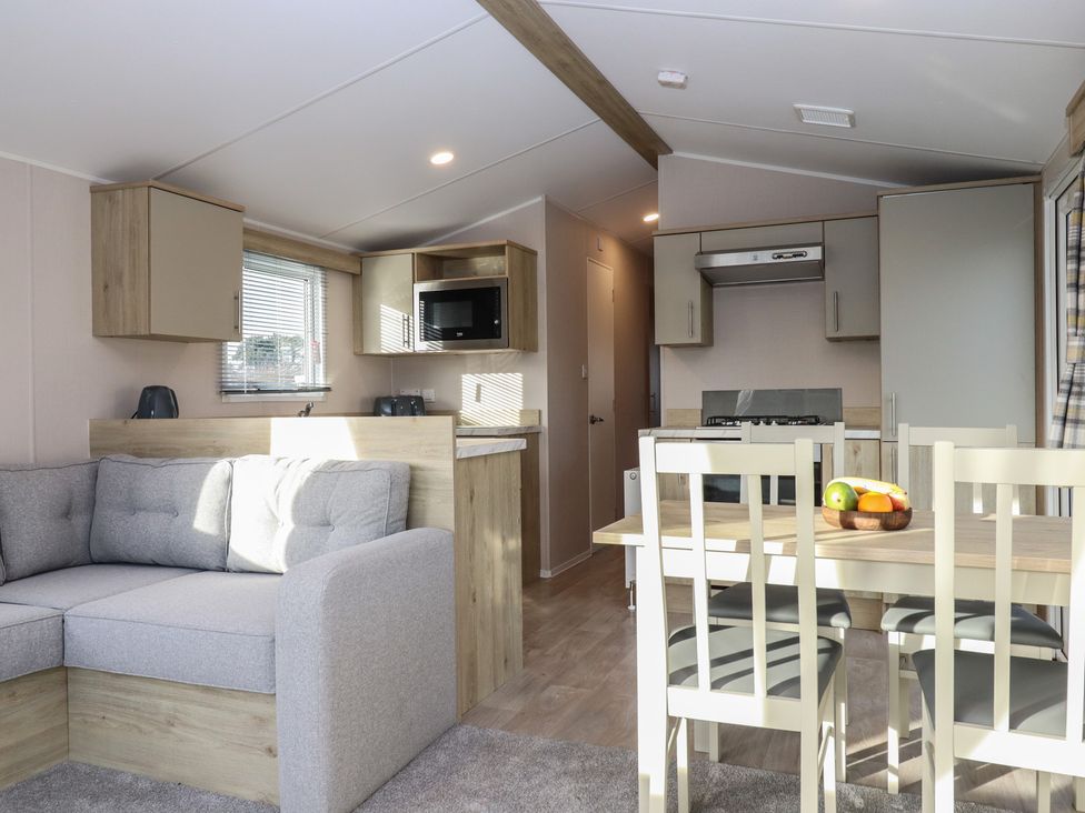 A living room and kitchen area with a sofa and dining table at Caravan B61 at Landscove Holiday Park Brixham