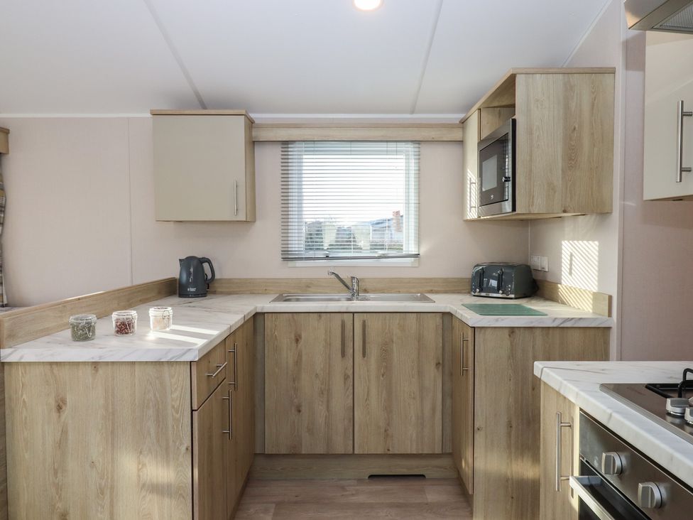 A kitchen with cabinets, a sink, and appliances at Caravan B61 at Landscove Holiday Park Brixham