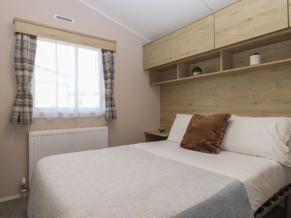 A bedroom with a bed and window at Caravan B61 at Landscove Holiday Park Brixham