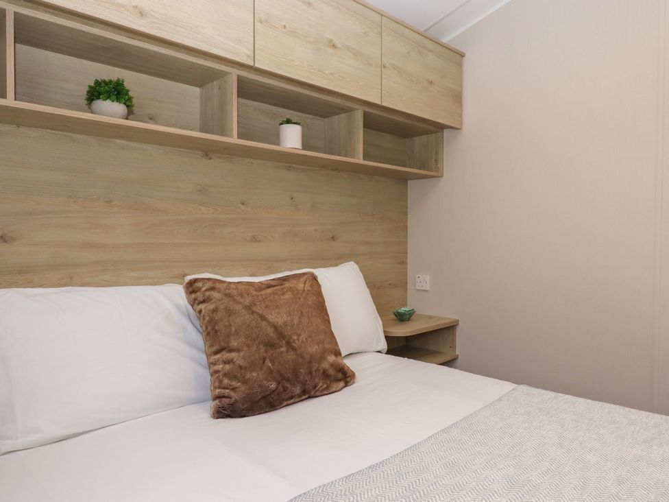 A bedroom with a bed and shelves at Caravan B61 at Landscove Holiday Park, Brixham