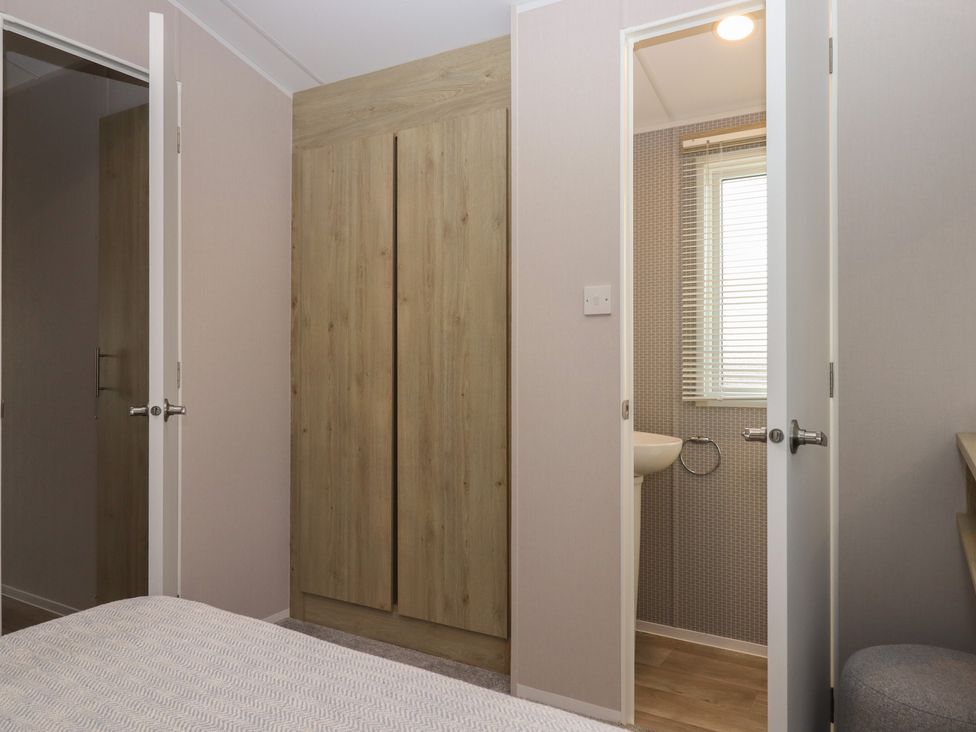 A bedroom with a wardrobe and bathroom doors at Caravan B61 at Landscove Holiday Park in Brixham