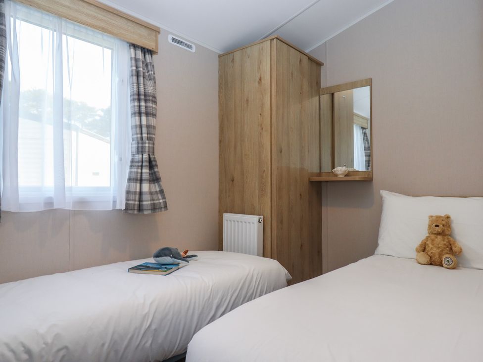 A bedroom with two beds and a teddy bear at Caravan B61 at Landscove Holiday Park in Brixham
