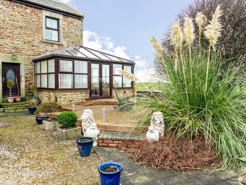 A garden with a conservatory and planters at Bank House Cottage in Lancaster