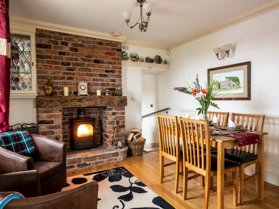 A dining room with a fireplace and a wooden table at Bank House Cottage in Lancaster
