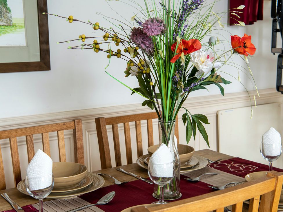 A dining table set with flowers and dinnerware at Bank House Cottage in Lancaster
